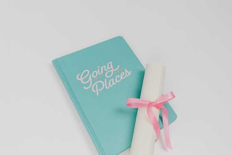 Green Notebook And White Rolled Paper With Pink Ribbon