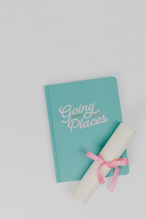 Free Rolled Certificate with Pink Ribbon on Top of a Notebook Stock Photo