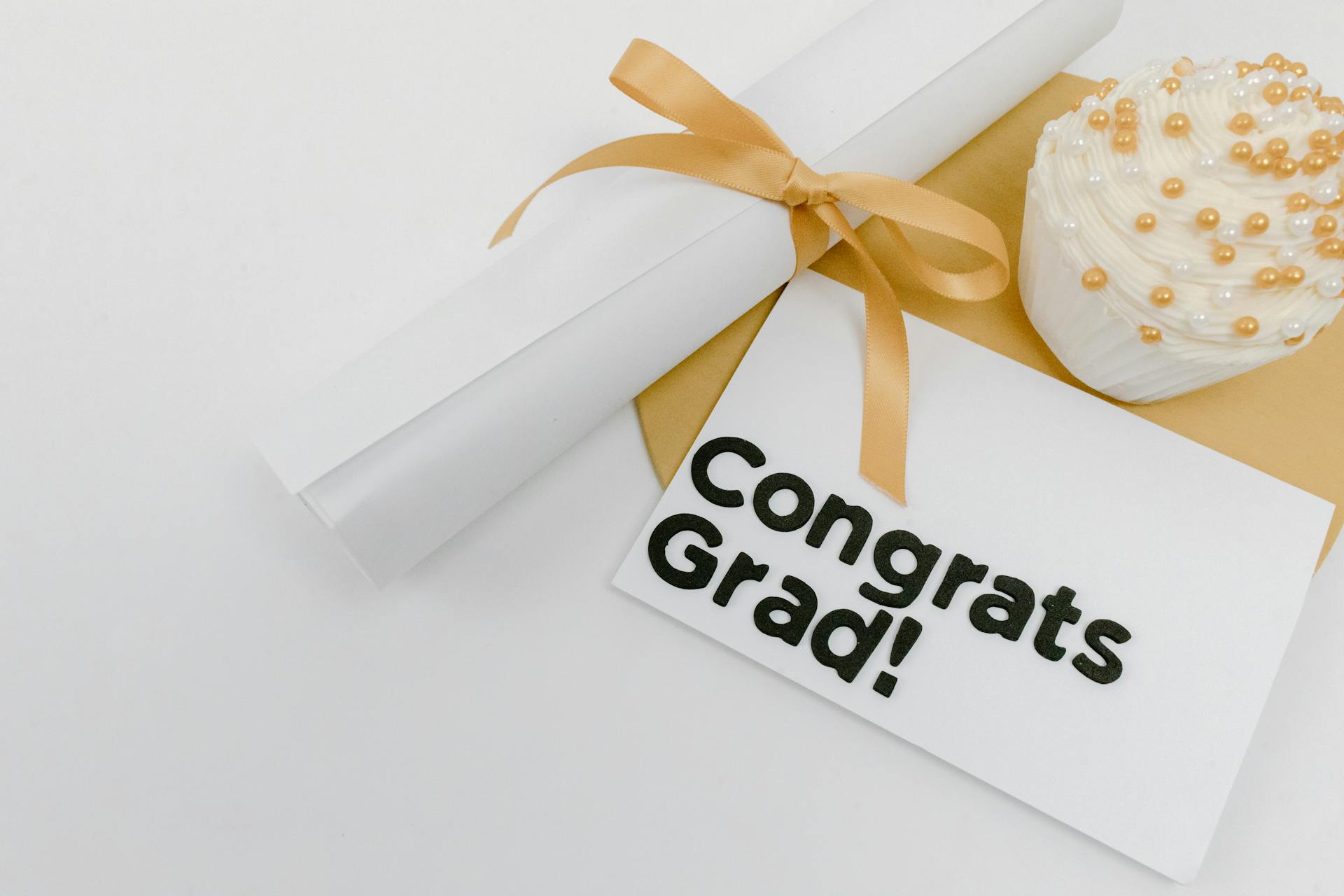 Graduation celebration scene with diploma, congrats card, and cupcake decoration.