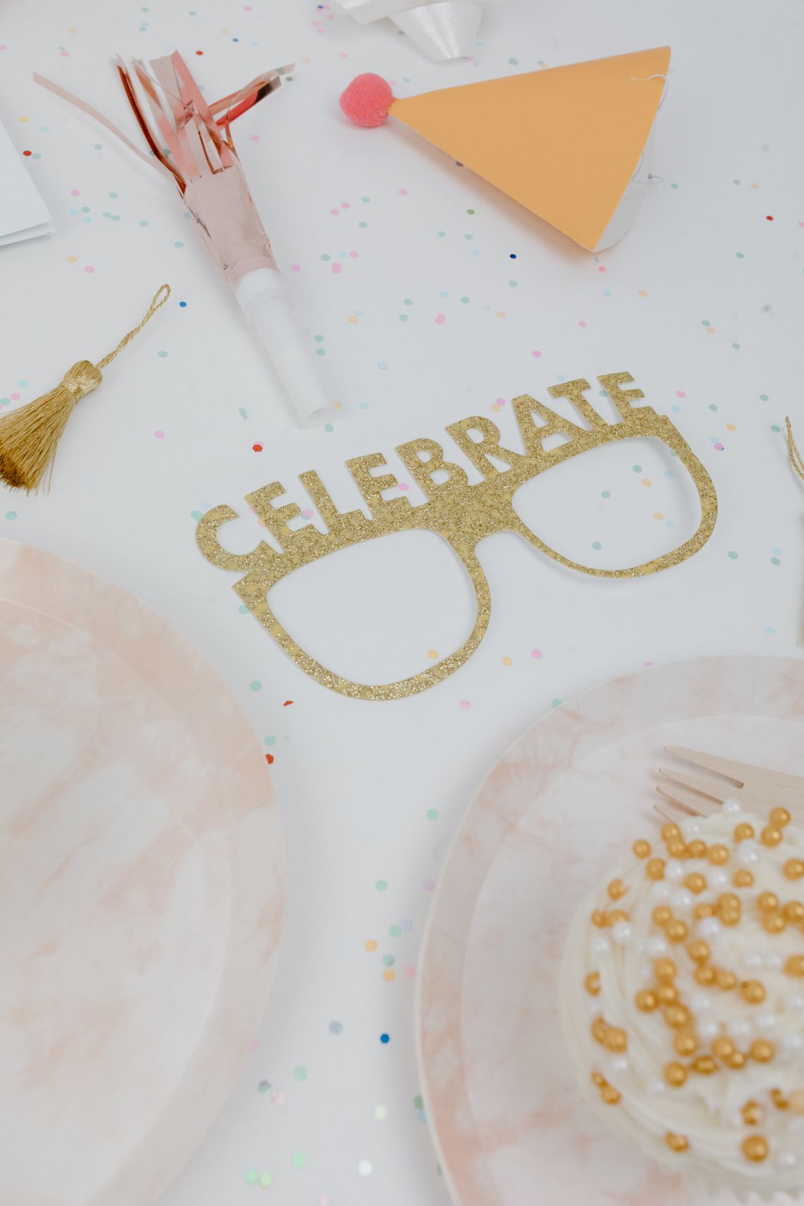 Elegant celebration table with confetti, cake, party accessories, and festive styling