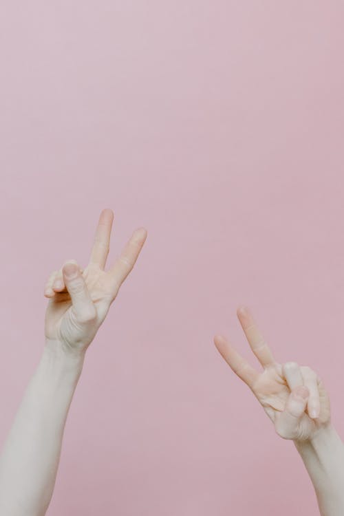 Free Persons Hands Doing a Peace Sign Stock Photo