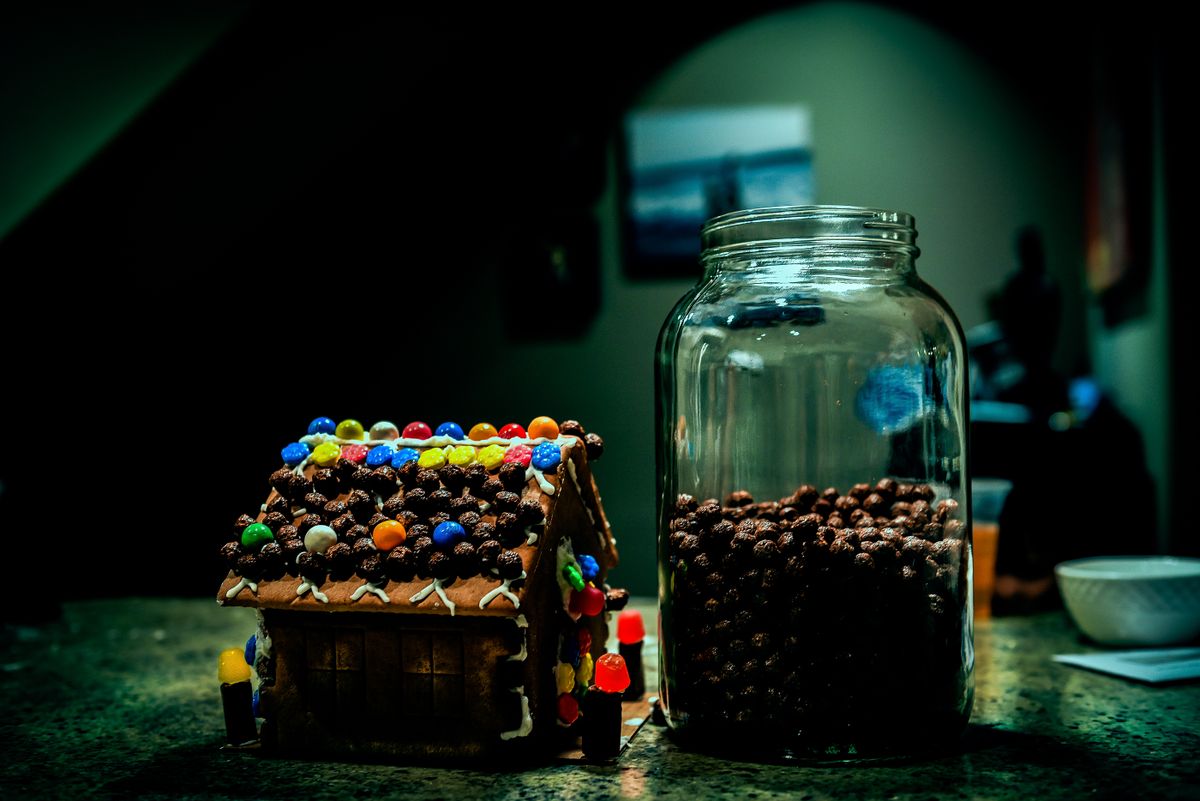Colorful gingerbread house with candy jar on indoor countertop. Perfect for holiday themes.