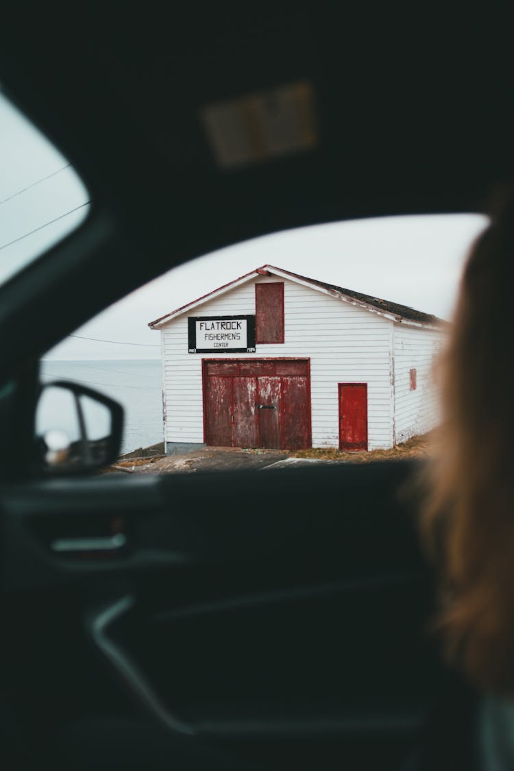 Unrecognizable Woman Observing Old House From Car