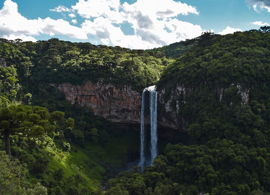 Explore the stunning waterfall amidst lush greenery in Gramado, Brazil.