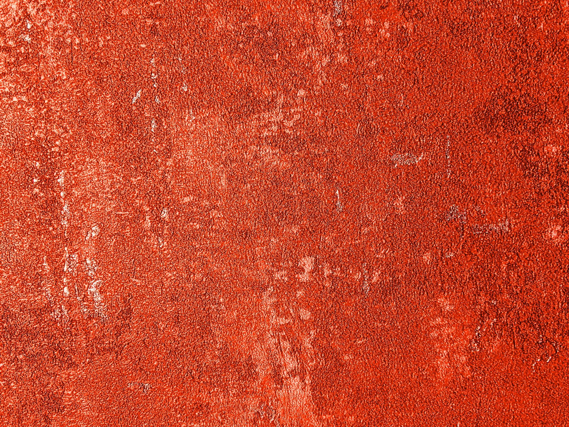 Background of textured shabby wall with red peeling paint and stains with spots of old fashioned building located on street