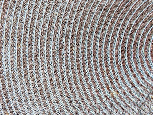 Top view closeup part of textured woven wicker gray placemat with round shaped elements with creative patterns placed on table