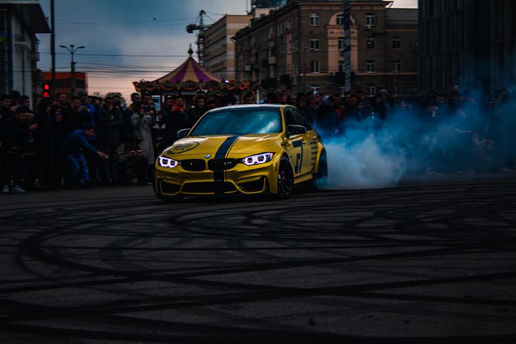 A Yellow BMW Drifting In Front Of The Crowd