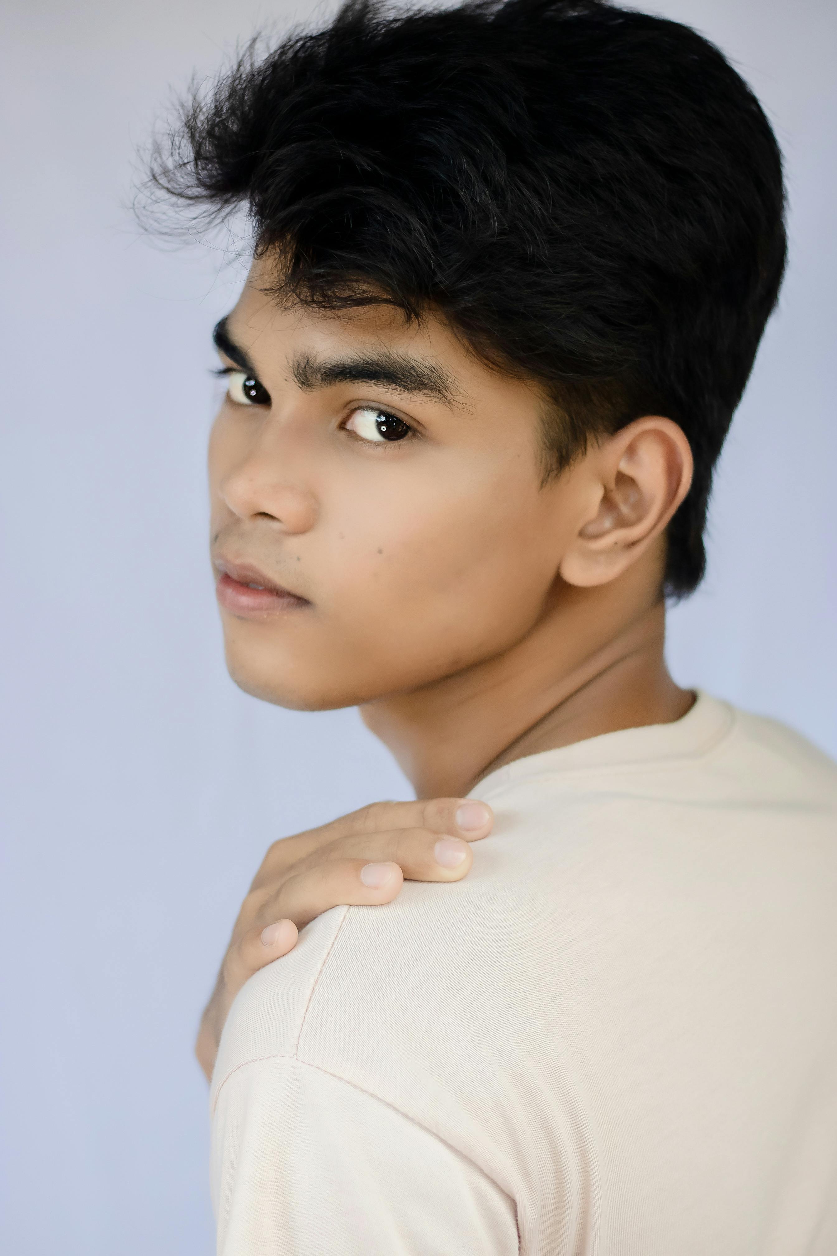 Handsome ethnic teenage male model touching shoulder and looking at ...