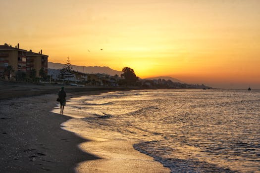 A solitary person walks along the beach at sunset, capturing the scenic view and tranquil atmosphere.