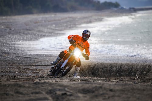 A Man in Orange Jacket and Black Helmet Riding a Motorcycle