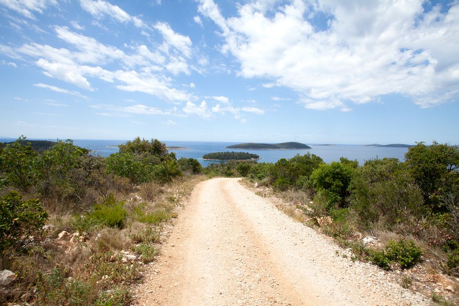 Picturesque dirt road with coastal view in Šolta, Croatia, under a bright summer sky.
