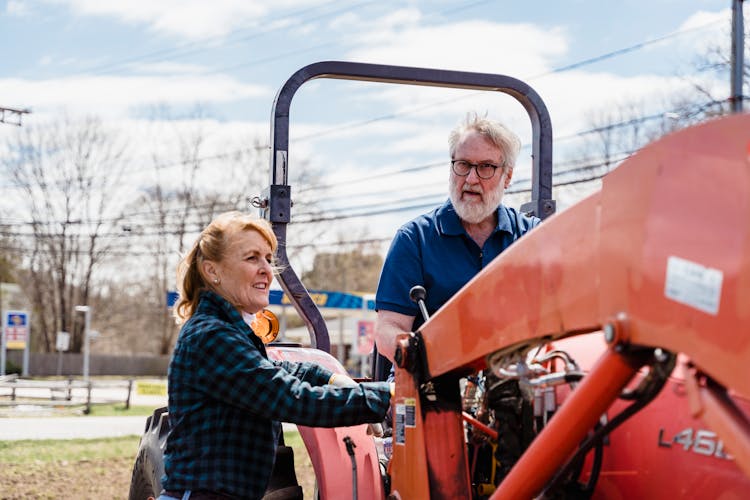 Woman Standing Near Man Driving Tractor On Street