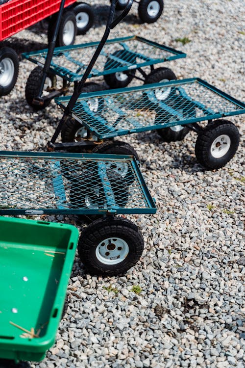 From above of small carts with black wheels and metal grid placed on stone ground in daytime