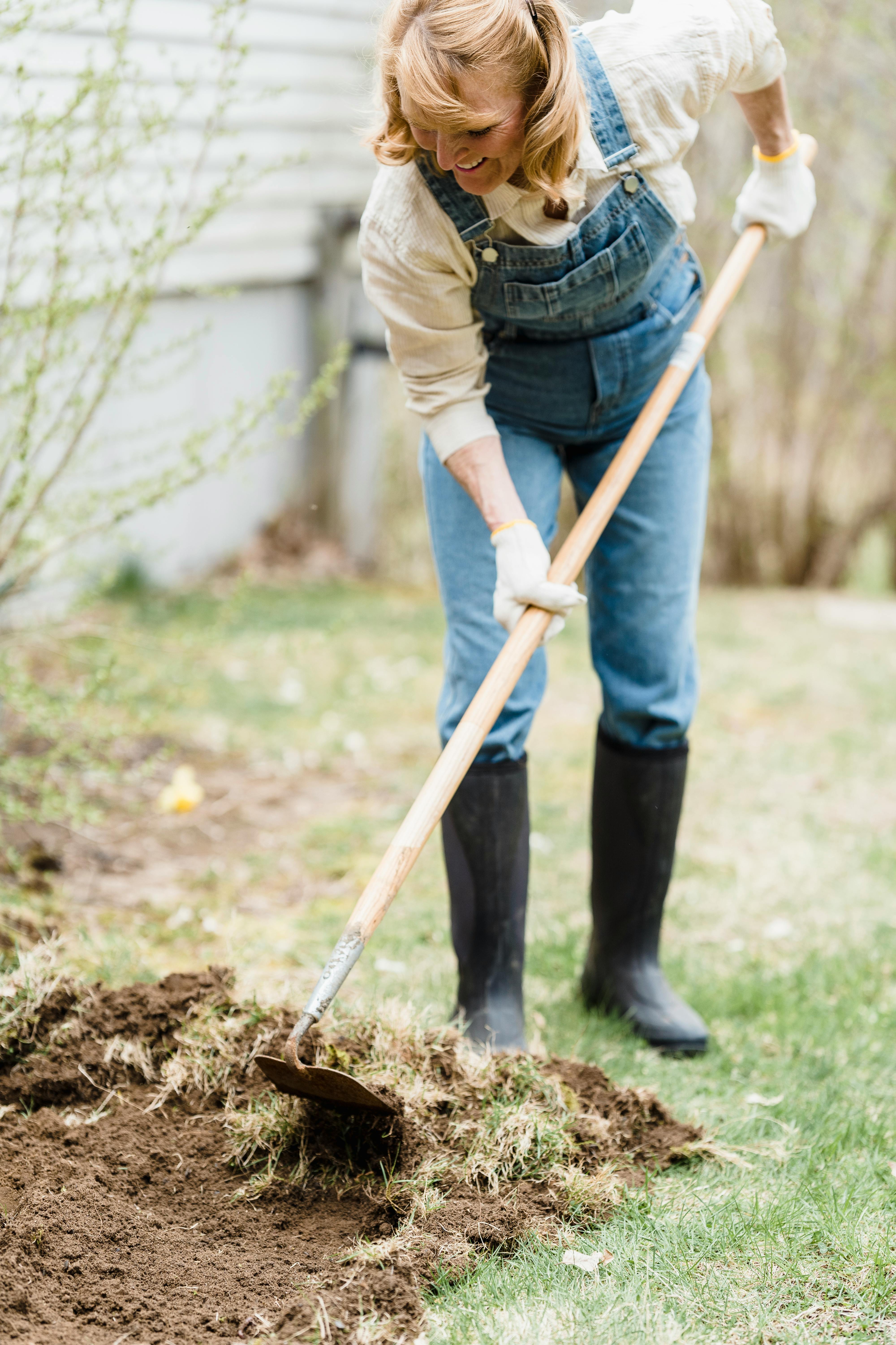 female farmer loosening ground in garden in countryside