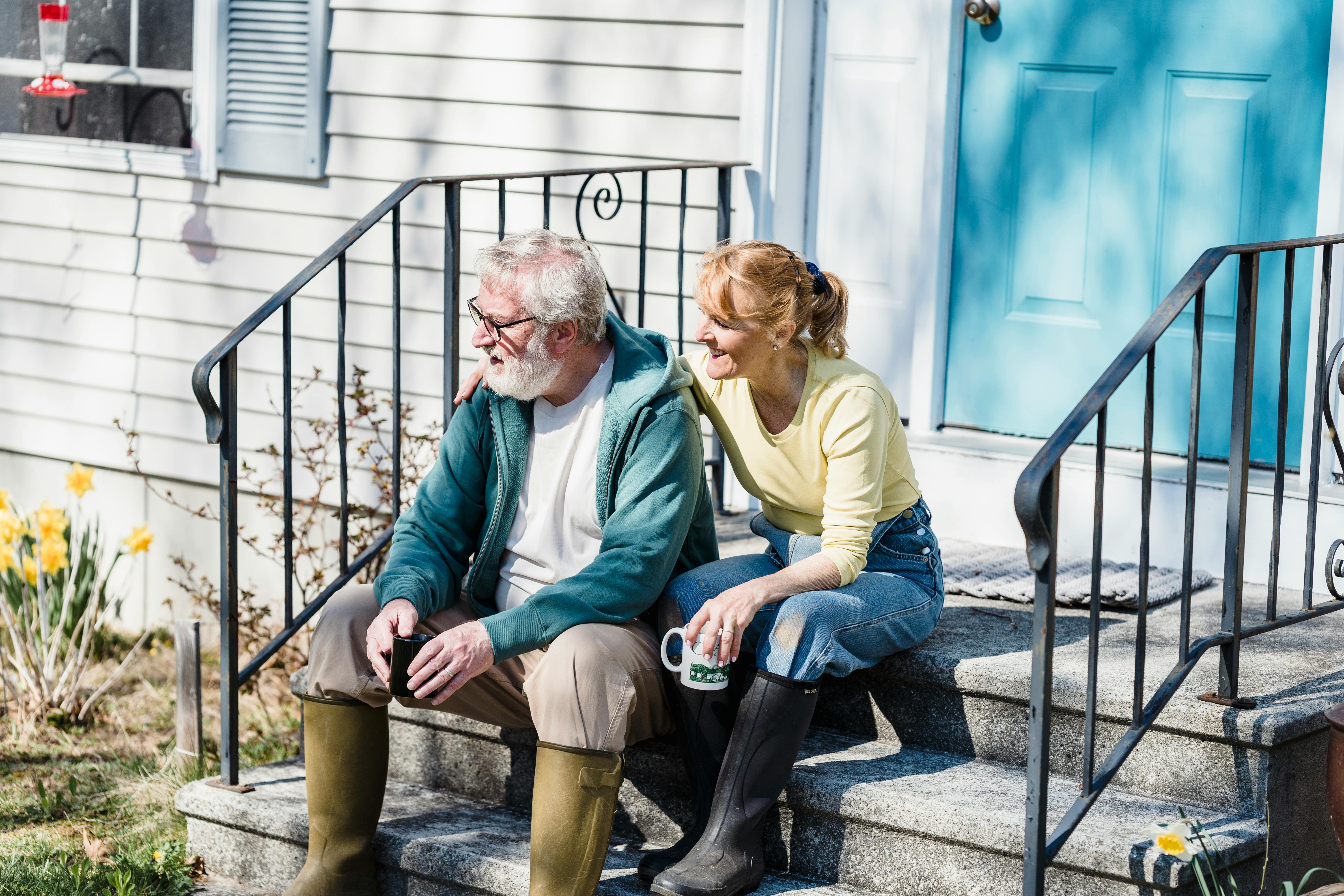 husband and wife sitting on porch with cups of tea