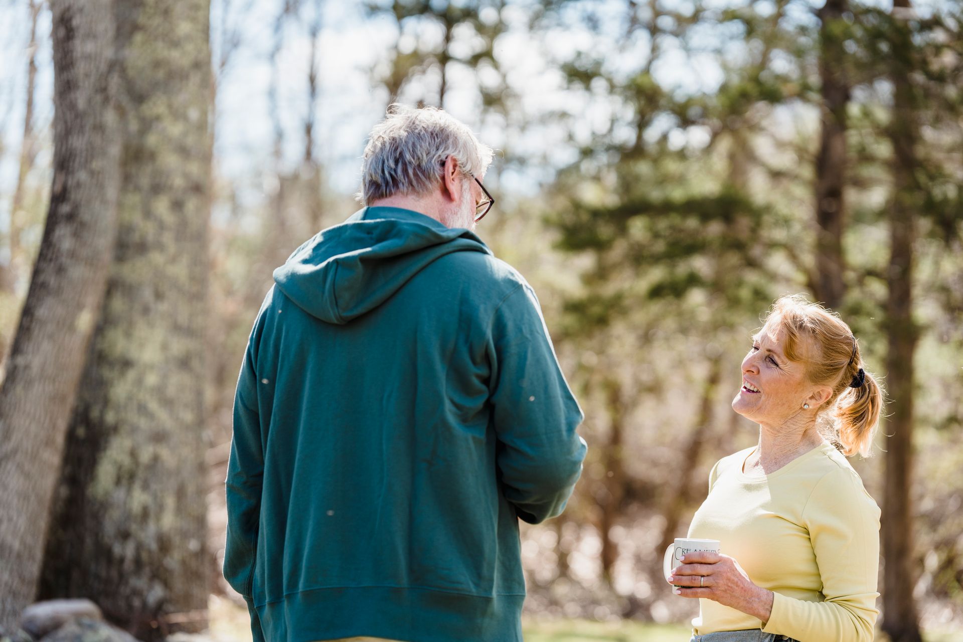 Senior couple enjoying a peaceful coffee chat outdoors on a sunny day in the forest.