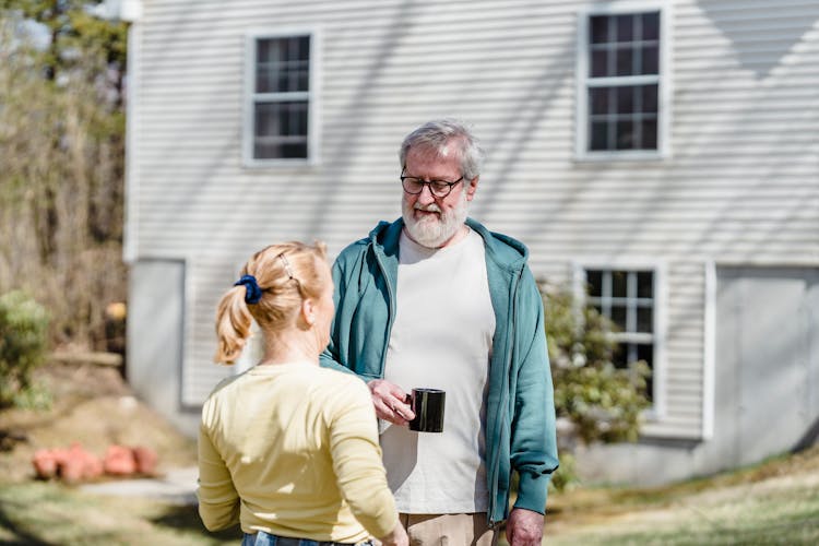 Senior Couple Spending Time In Yard Of Suburban House