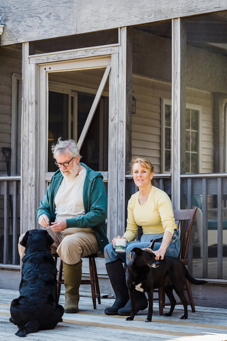 Aged Couple With Dogs On Wooden Terrace