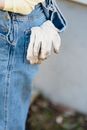 Dirty white gloves in back pocket of crop faceless person jeans on blurred background