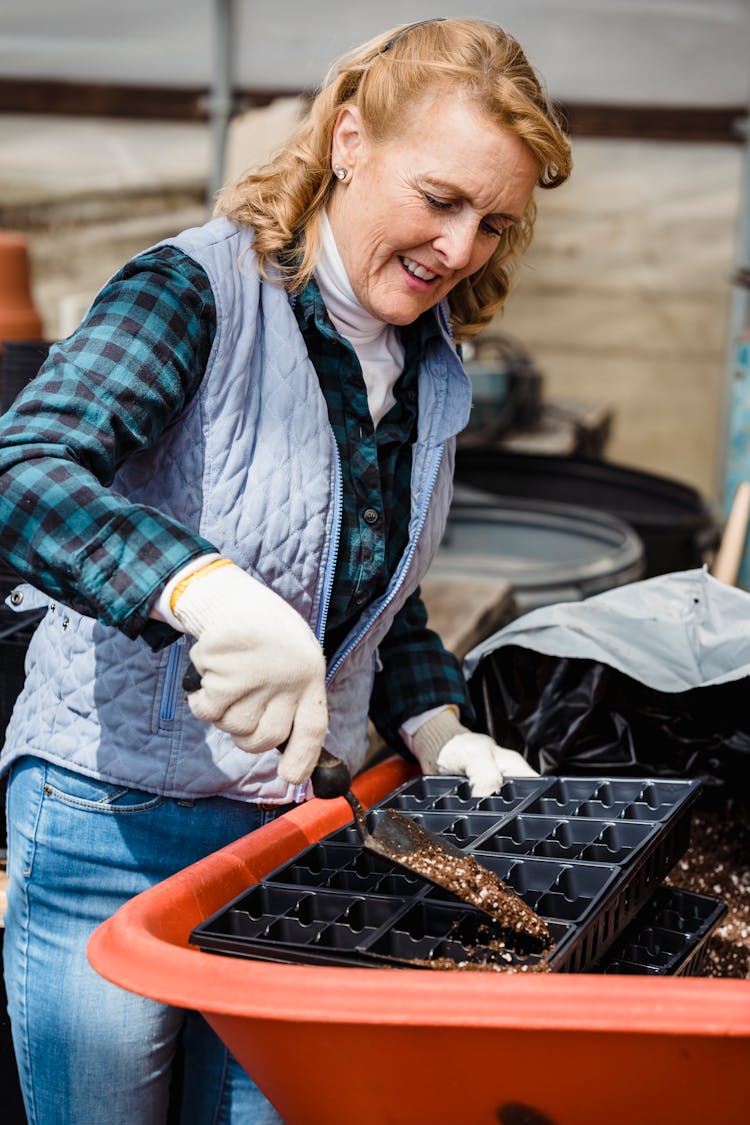 Cheerful Senior Gardener Putting Soil In Container