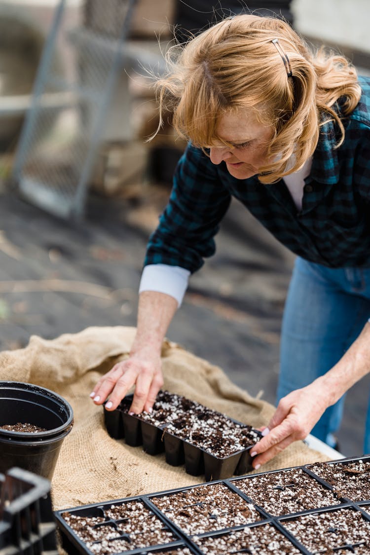 Senior Woman Planting Seeds In Container