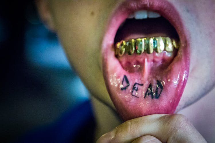 Photography Of Man Showing Tattoo And Gold Teeth