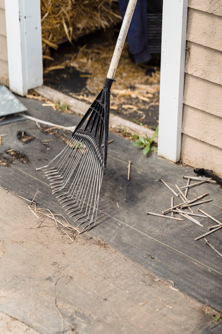 Crop Metal Rake Near Wooden Barn