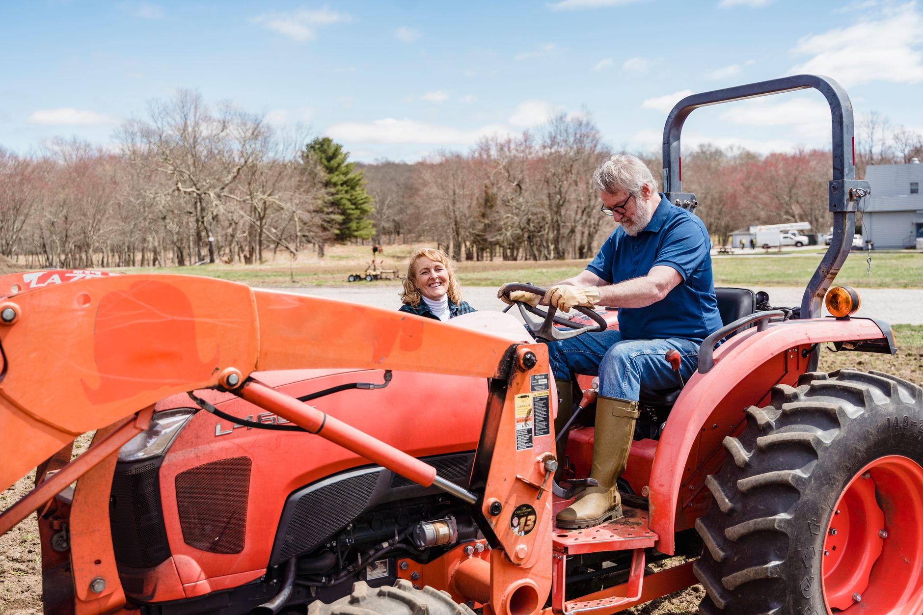 Senior couple sharing a joyful moment on a tractor ride in a countryside farm setting.