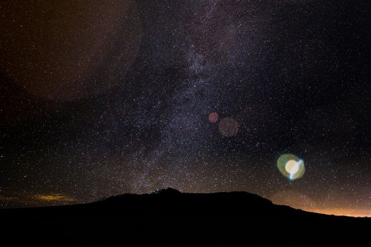 Capture the beauty of a starry night sky over a mountain silhouette, perfect for astronomy enthusiasts.