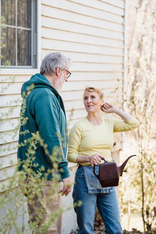 Free Elderly couple enjoys gardening together outside their home, sharing a moment of conversation. Stock Photo