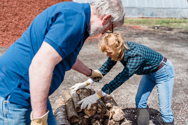 Elderly Couple Piling Wood Logs Together