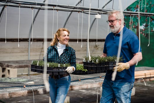 Elderly couple enthusiastically tending to plants in a greenhouse, enjoying horticulture.