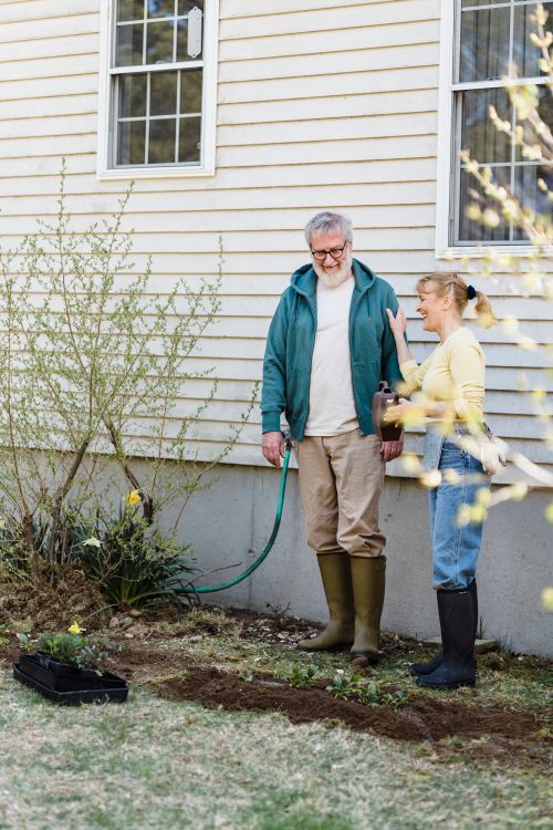 Free Elderly couple gardening outside their home with joy and happiness. Stock Photo