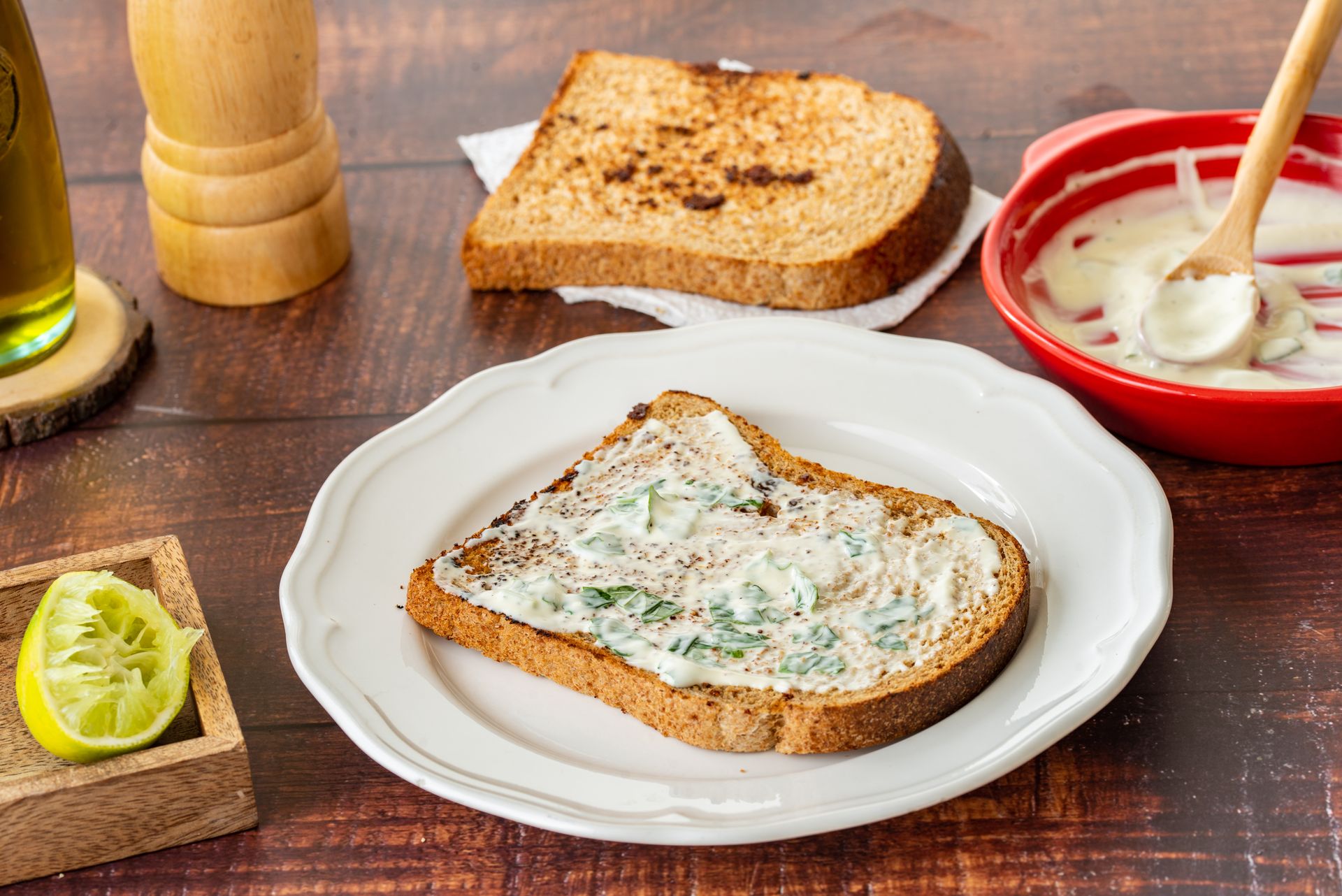Rustic toast with a creamy herb spread and lemon wedge, perfect for a tasty breakfast.