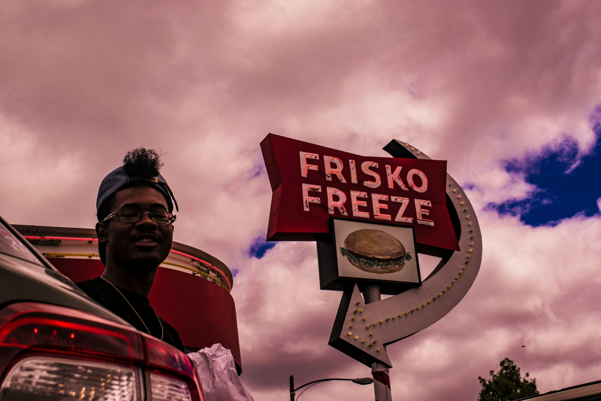 Man In Baseball Cap Near Frisko Freeze Signage