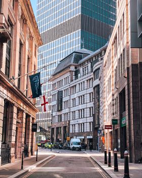 A sunlit street lined with historic and modern buildings in a bustling urban center.