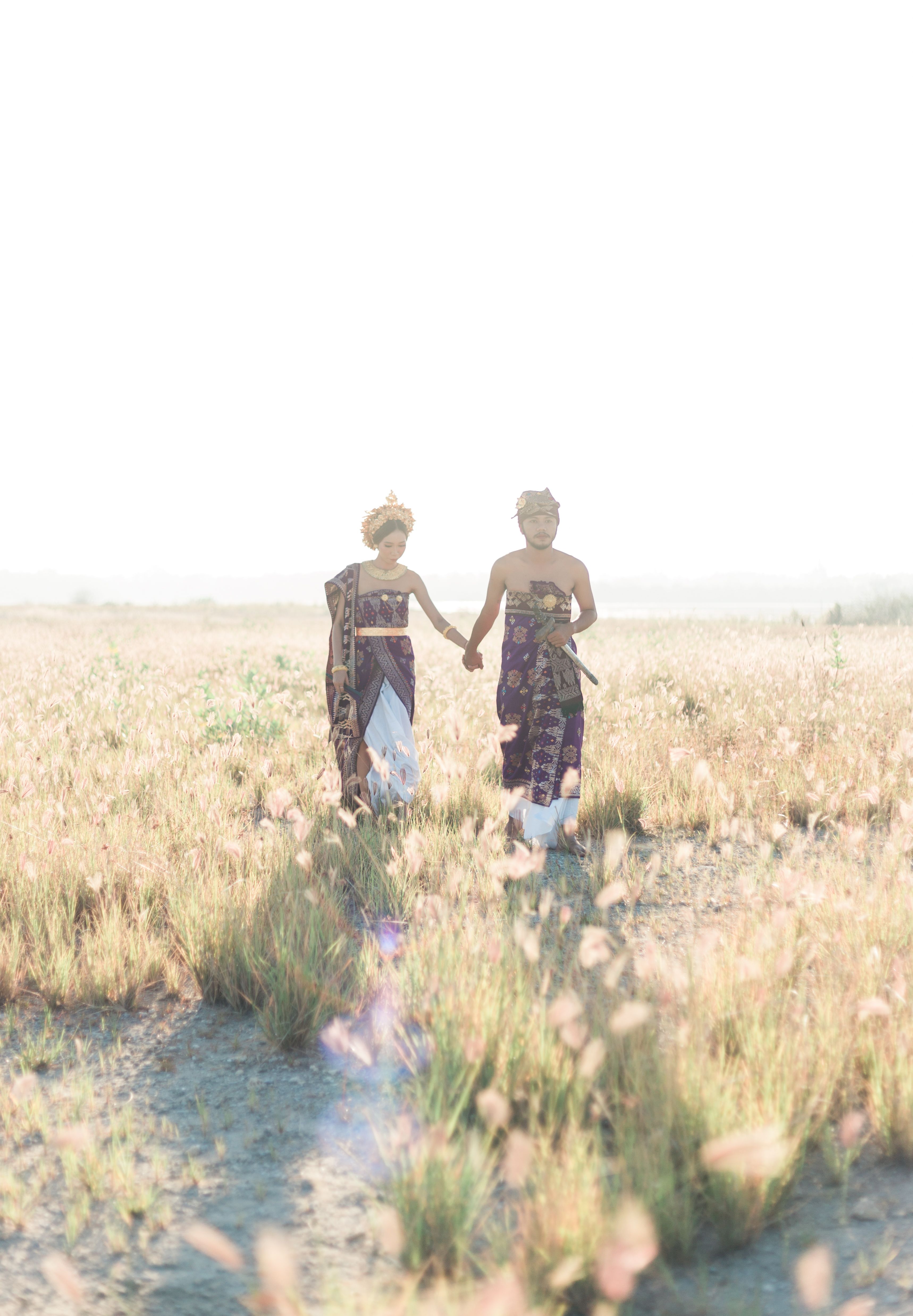 A Coupe Walking on the Grass Field While Holding Hands · Free Stock Photo