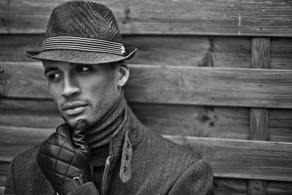 Black and white portrait of a man in a fedora hat, against wooden background in Paris.