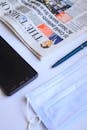 Smartphone Near the Newspaper on the White Surface