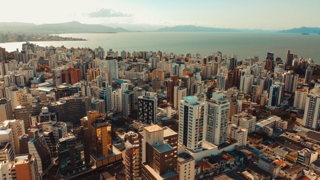 Aerial view of Florianópolis with skyscrapers and ocean backdrop under a clear sky.