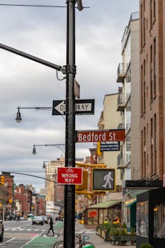 Street view of Bedford Street in New York City showcasing street signs and urban life.