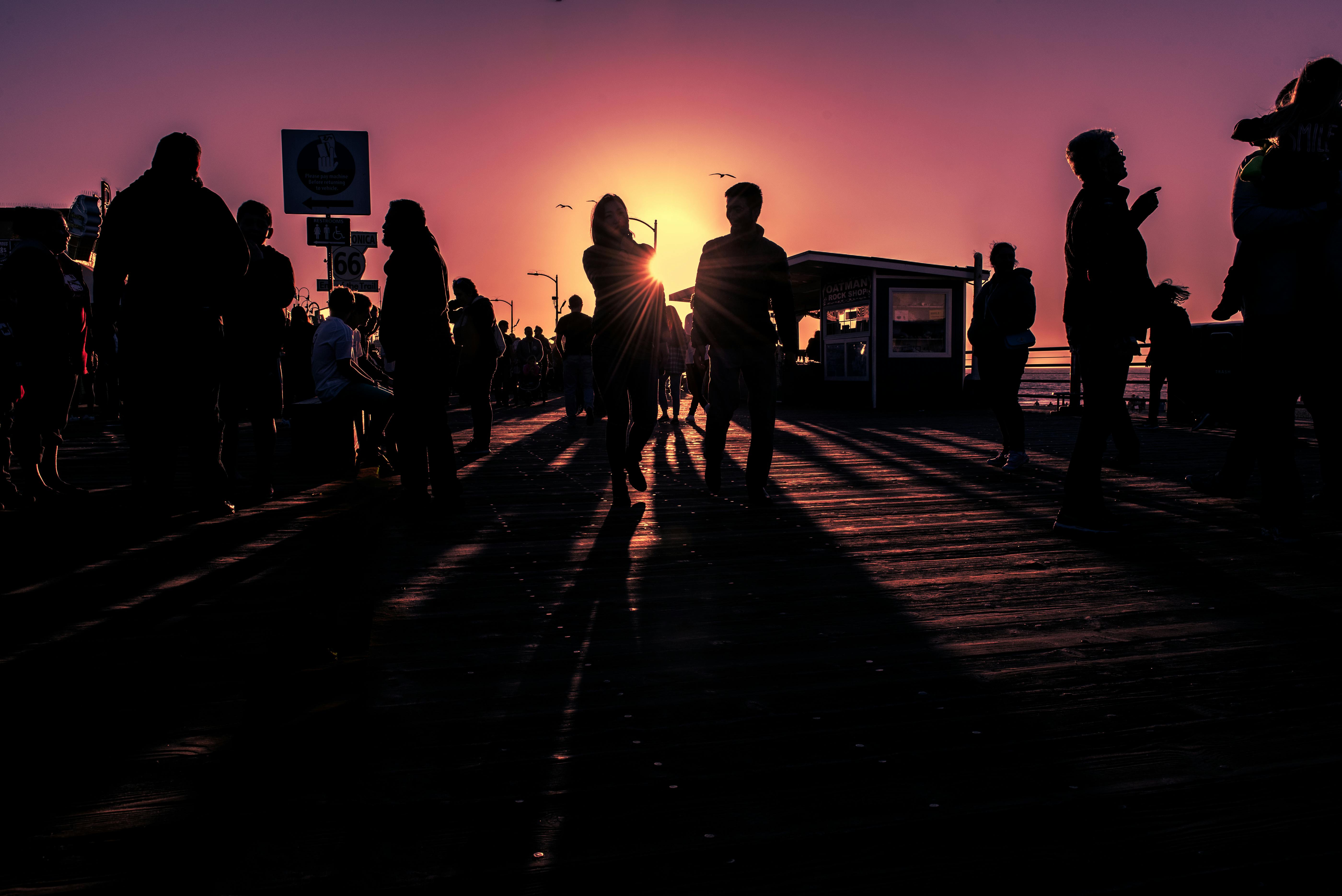 日落映照下的码头五彩缤纷，人们的轮廓充满活力，营造出戏剧性的氛围