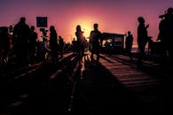 日落映照下的码头五彩缤纷，人们的轮廓充满活力，营造出戏剧性的氛围