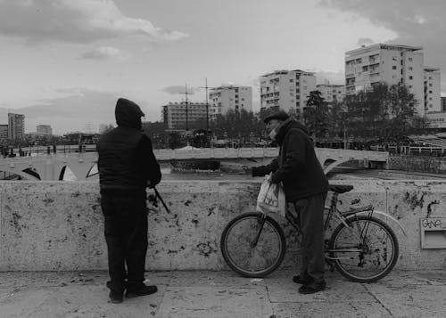 Monochrome Photo of a Man with a Bicycle Talking to Another Man