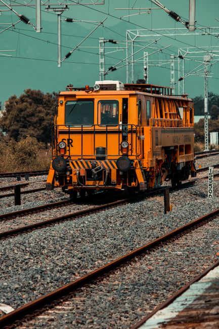 Fotomural Una vibrante locomotora amarilla en las vías del tren en India, mostrando la infraestructura de transporte.