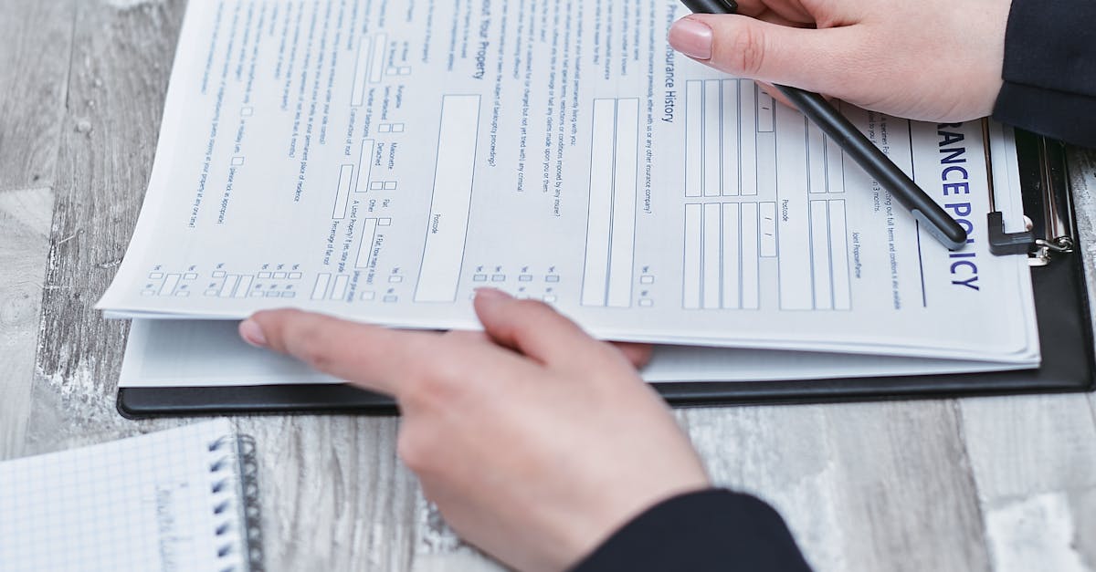 Photo by Mikhail Nilov Close-up of hands analyzing insurance policy paperwork with pen on table.