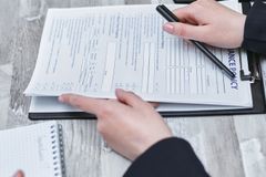 Close-up of hands analyzing insurance policy paperwork with pen on table.