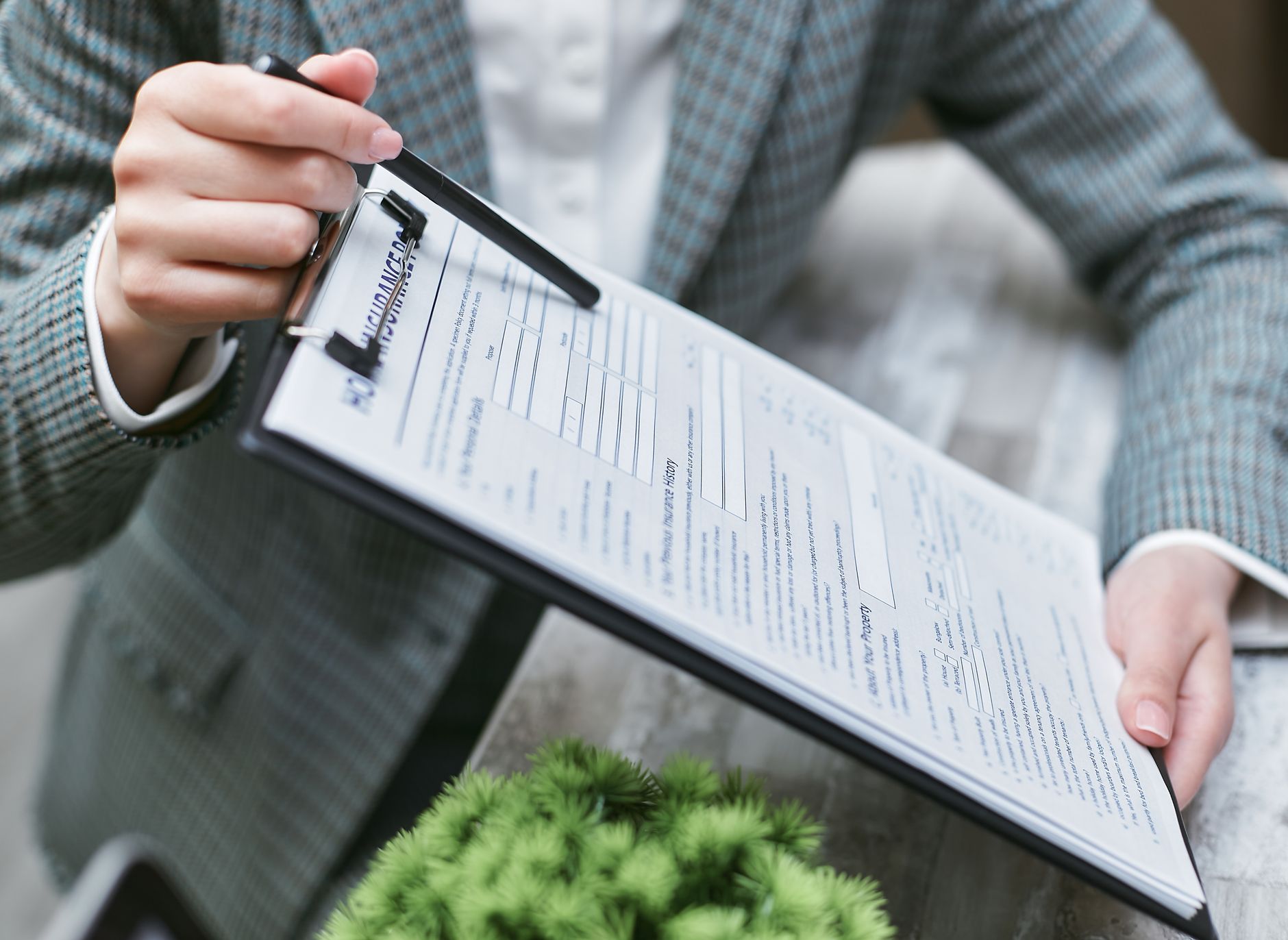 Hands holding a clipboard with an insurance document, reviewing coverage limits and loss settlement terms