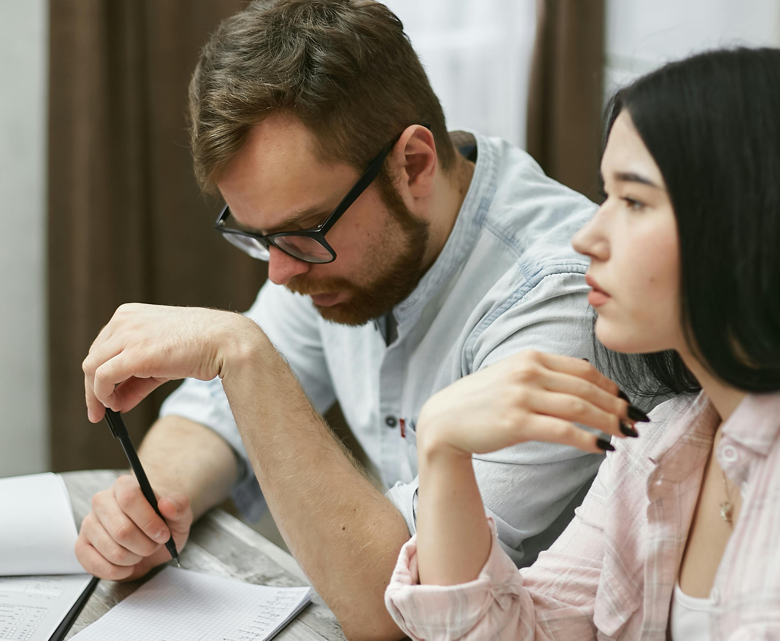 A man and woman collaborating on a project in an indoor office environment.