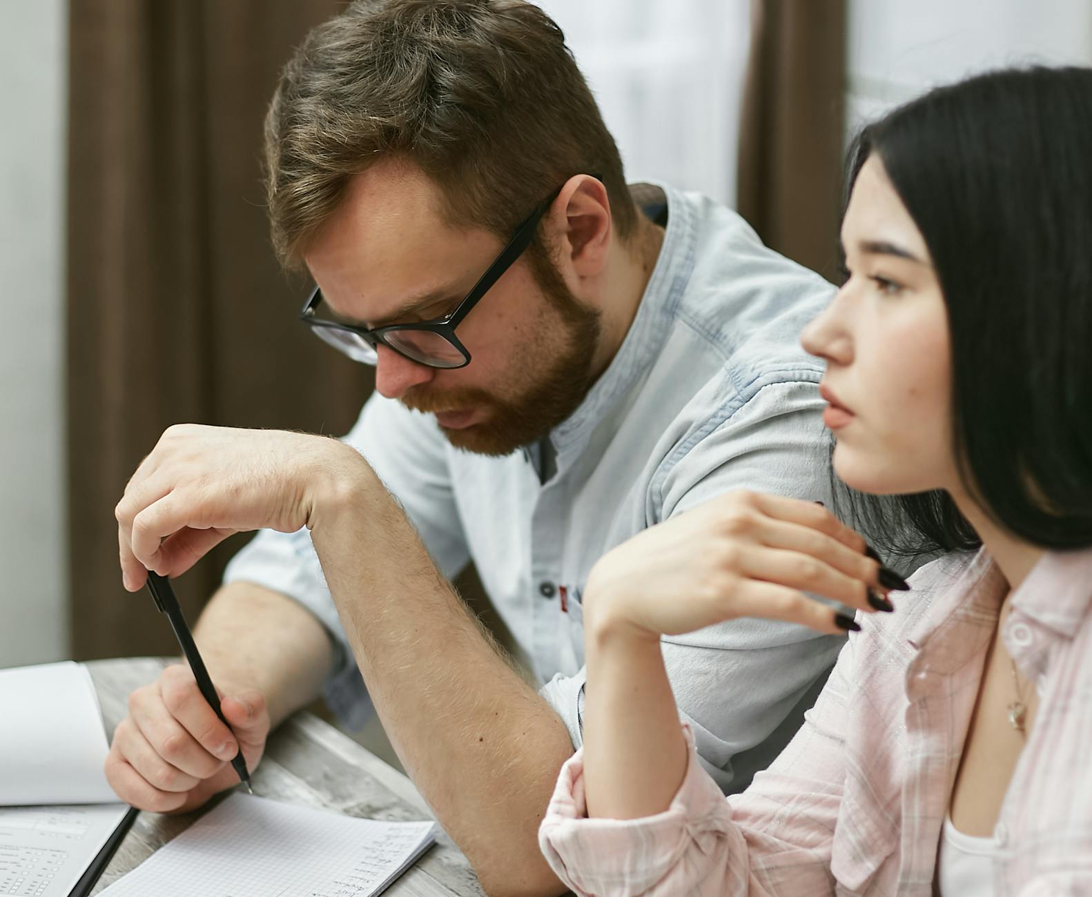 A man and woman collaborating on a project in an indoor office environment.